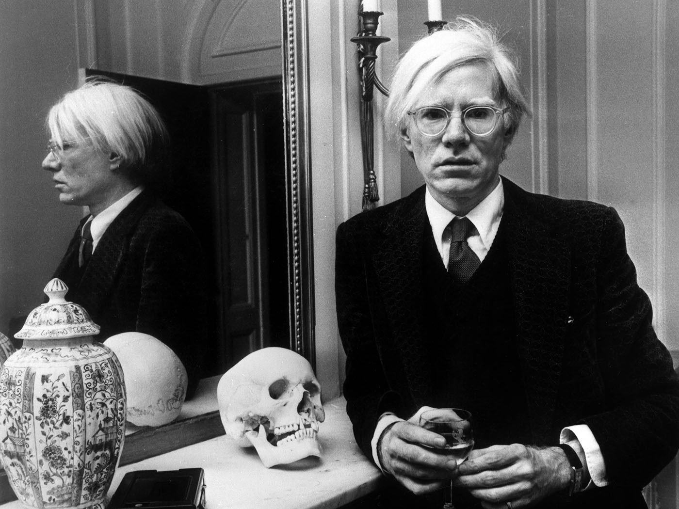 Andy Warhol lent on mantel piece wearing Cartier Tank in Understanding Andy Warhol as a collector for A Collected Man